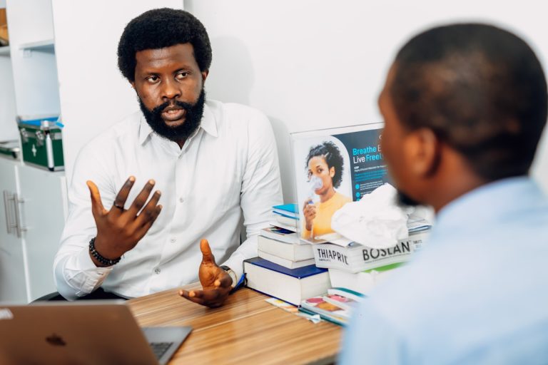 A man sitting at a desk talking to another man